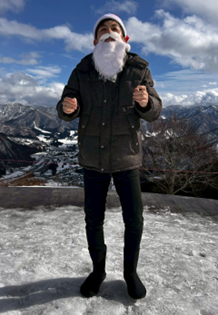 雪山をバックにサンタクロースの衣装とひげを身につけた男性