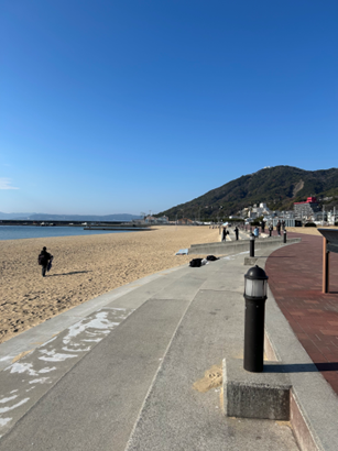 青空の下、遊歩道に沿って広がる砂浜と海の風景