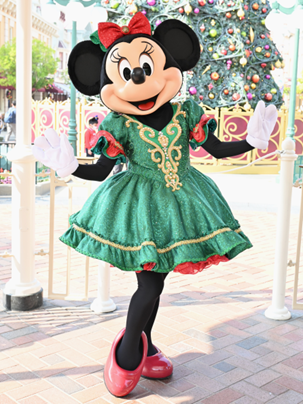 クリスマスツリーの前で緑のドレスを着てポーズをとるミニーマウス