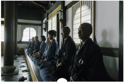 お寺の堂内で静かに座禅を組む僧侶と参拝者たち