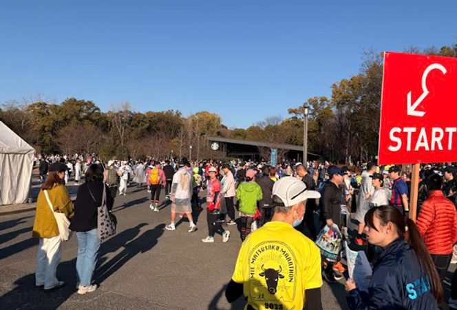 マラソン大会のスタート地点付近に集まるランナーやスタッフたち