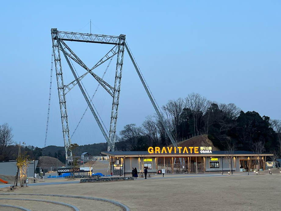 巨大な金属製タワーの前に立つ「GRAVITATE OSAKA」の施設建物