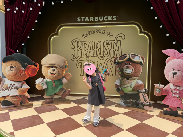 スターバックスのベアリスタたちの大きなパネル前で、ポーズをとる子ども