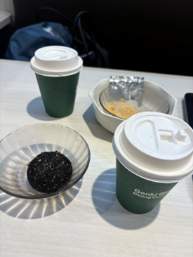 テーブルの上に並べられた、紙コップの温かいドリンクと和菓子（胡麻団子、きな粉餅）