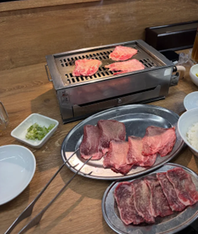 卓上コンロで牛タンを焼きながら、手前の皿に盛られた牛タンやカルビを楽しむ焼き肉の様子