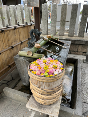 鮮やかなピンクや黄色の花々が敷き詰められた手水鉢と、竹の柄杓が用意された手水舎